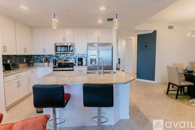 A kitchen with a granite countertop and bar stools.
