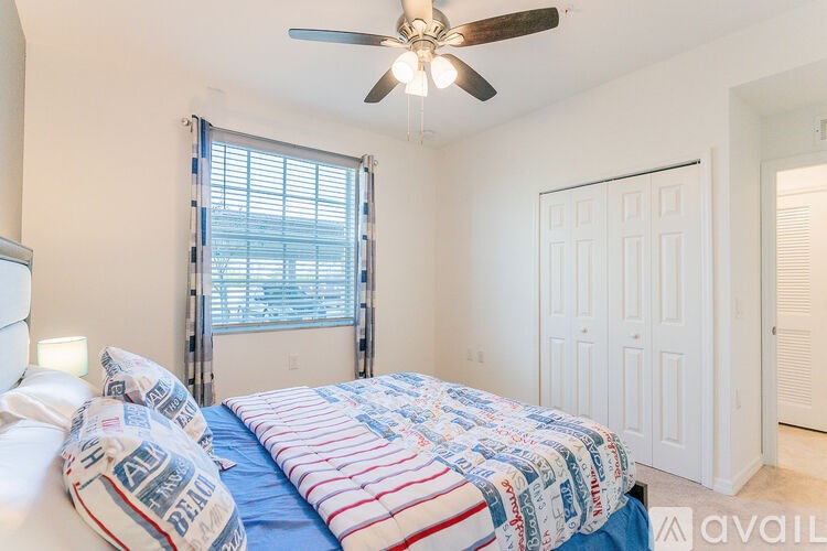A bedroom with a bed, pillows, and a ceiling fan.