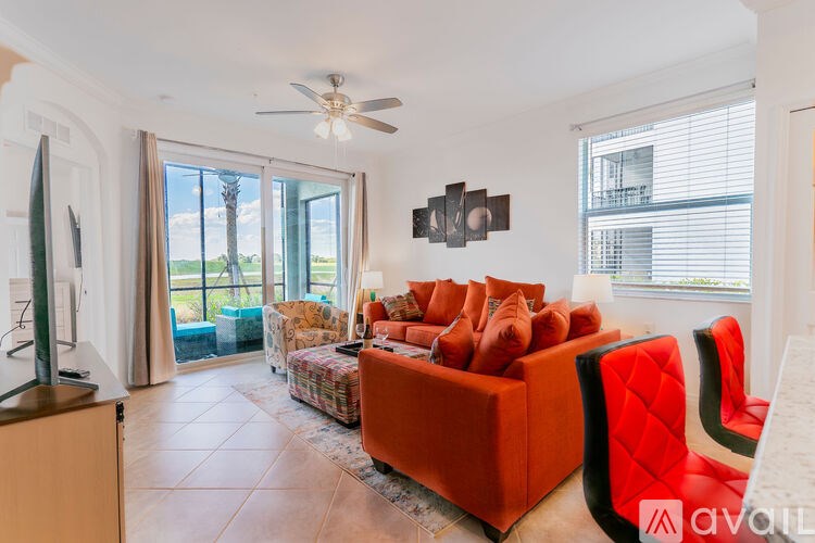 A living room with a television, orange couch, and a ceiling fan.