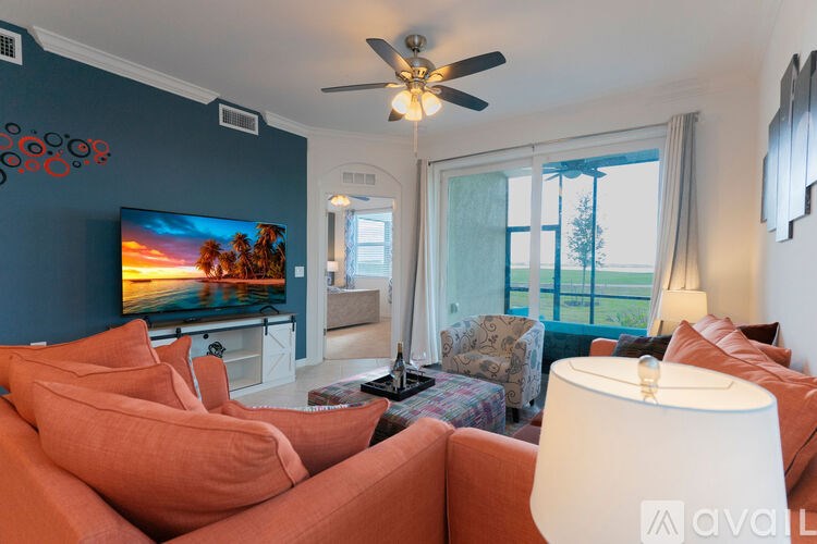 A living room with orange chairs and a flat screen TV.