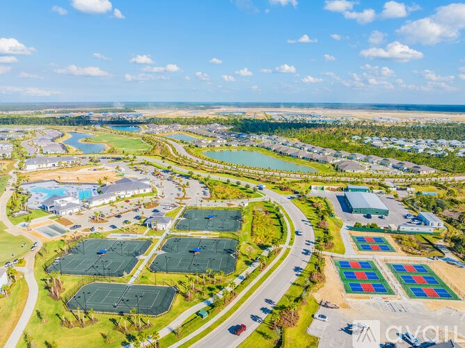 A bird's eye view of a residential area with multiple houses, roads, and green spaces.