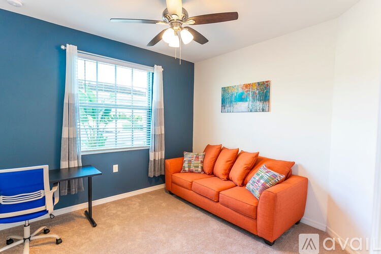 A living room with a blue wall and a ceiling fan.