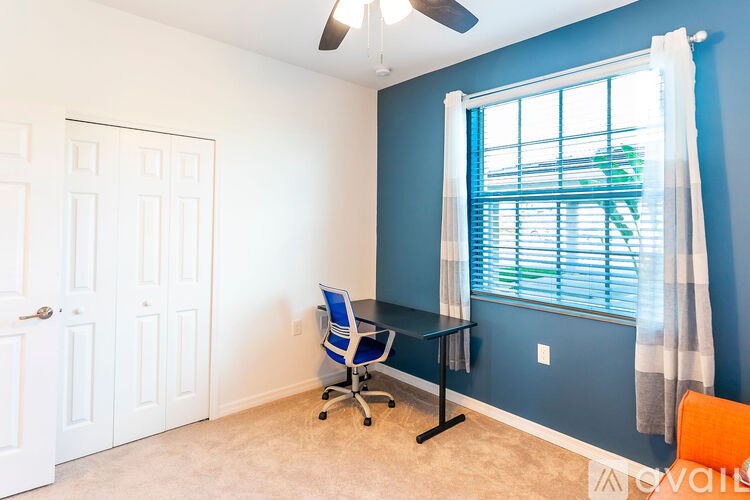 A room with a blue wall and a window with white curtains.