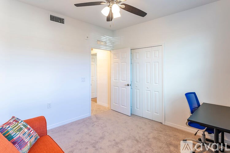 A room with a ceiling fan, a couch, and a table.