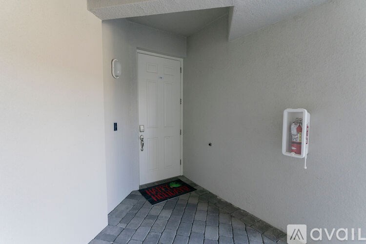 A white door is in a room with a red mat on the floor.