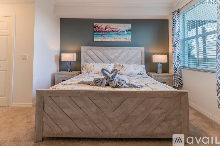 A bedroom with a large bed and a painting on the wall.