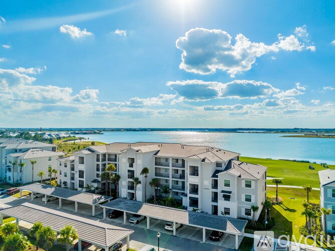 A sunny day at a resort with a large building and a parking area.