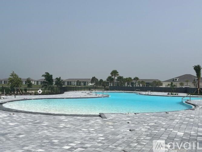 A large outdoor swimming pool surrounded by a grey tiled floor.