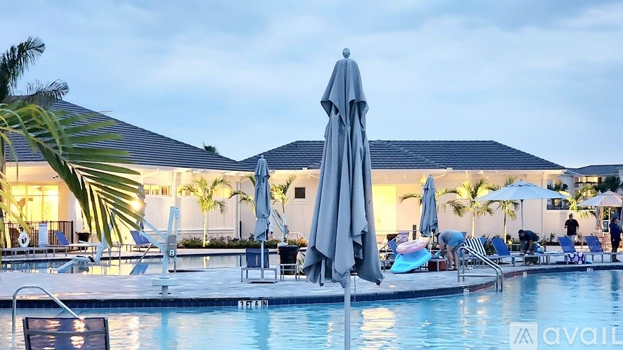A poolside scene with a large umbrella and chairs.