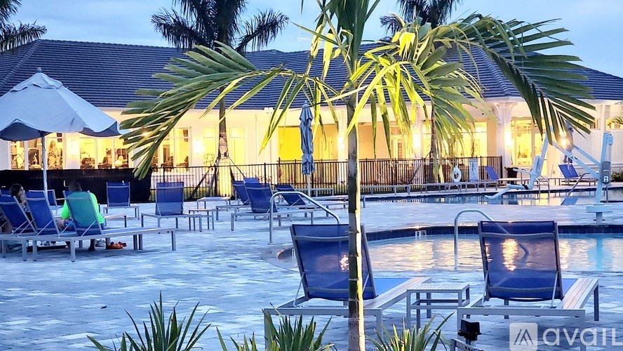 A pool area with lounge chairs and palm trees.