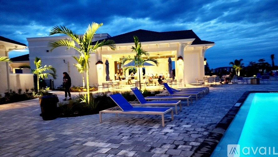 A poolside area with a person standing and chairs around a pool.