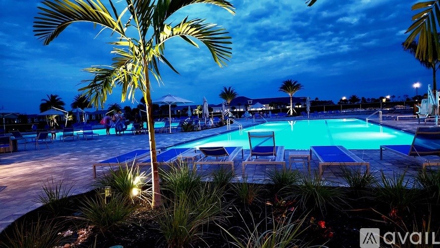A pool surrounded by palm trees at night.