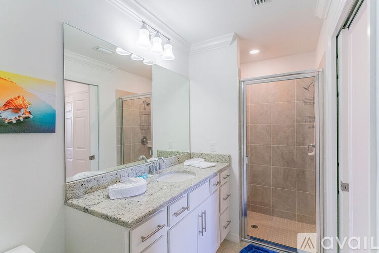 A bathroom with a marble countertop and a walk-in shower.