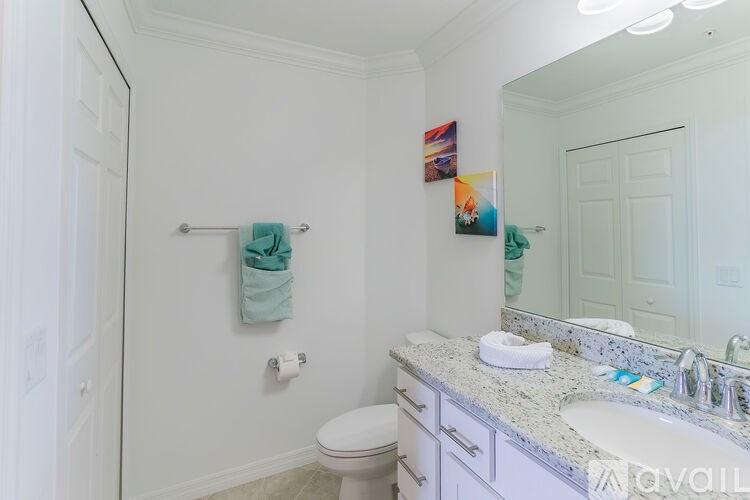 A white bathroom with a toilet, sink, and mirror.