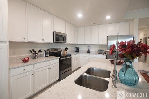 A kitchen with white cabinets and a stainless steel sink.