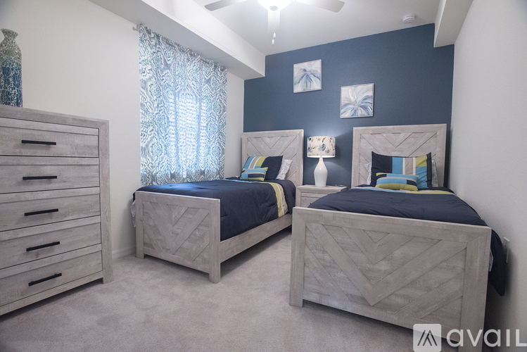 Two twin beds in a bedroom with a dresser and a window with curtains.