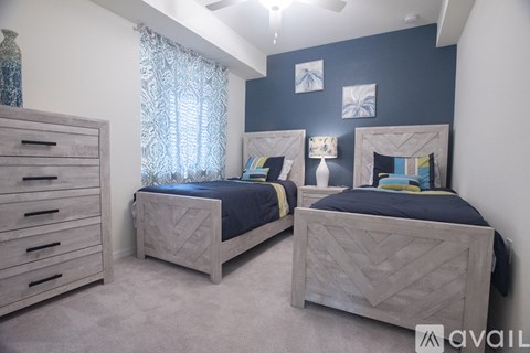 Two twin beds in a bedroom with a dresser and a window with curtains.