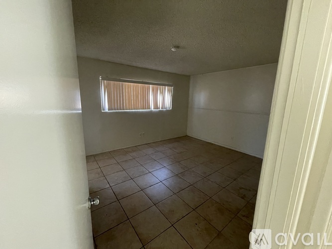 A room with tiled flooring and a window with blinds.