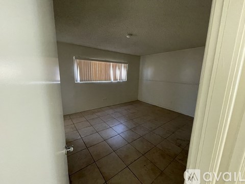 A room with tiled flooring and a window with blinds.