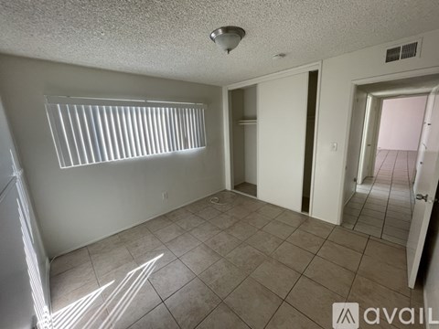 A room with a tiled floor and a window with blinds.