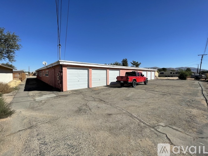A red truck is parked in front of a two-story building with a garage door.
