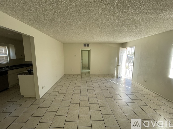 A spacious room with tiled flooring and a door in the middle.
