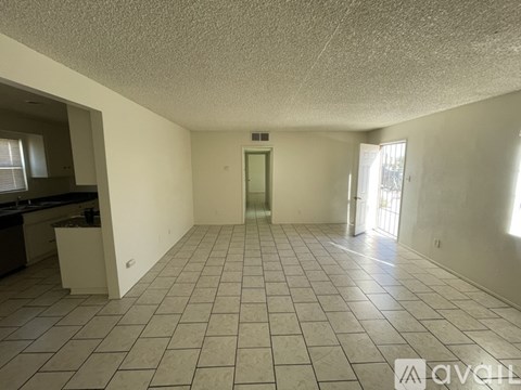 A spacious room with tiled flooring and a door in the middle.