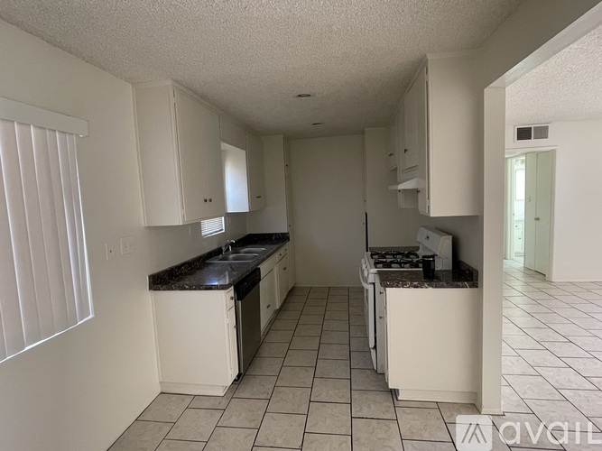A kitchen with white cabinets and a black countertop.