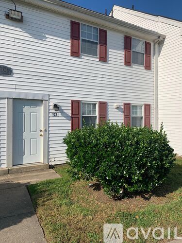 A white house with a blue door and red shutters.