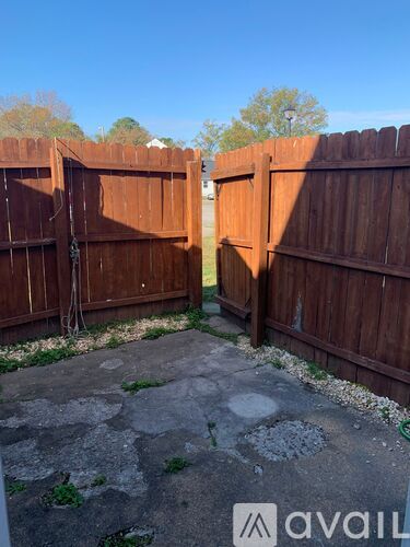 A wooden fence with a gate is in front of a grassy area.