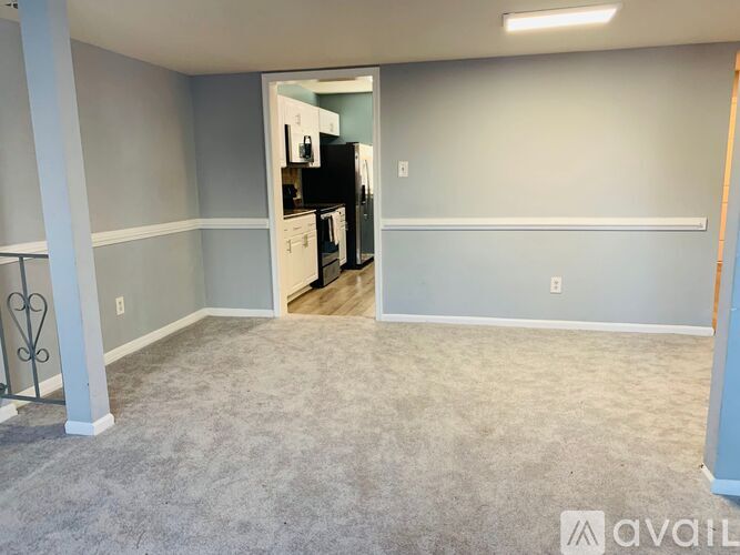 A kitchen area with a refrigerator, microwave, and oven is visible through an open door.