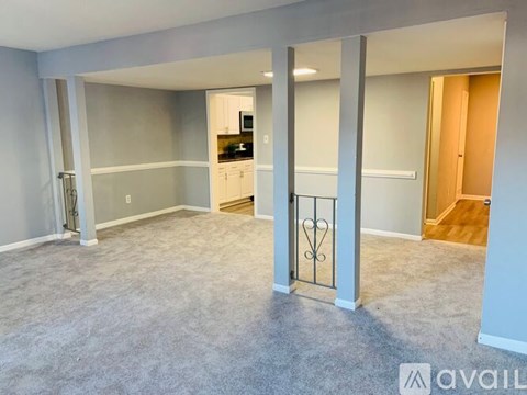 A spacious living room with a television and a kitchen in the background.
