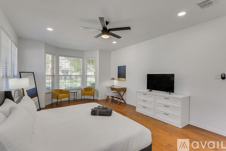 A bedroom with a large bed, a television, and a seating area with chairs.