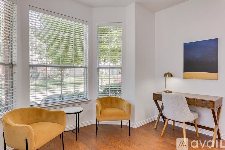 A room with a yellow chair, a white chair, and a brown desk.