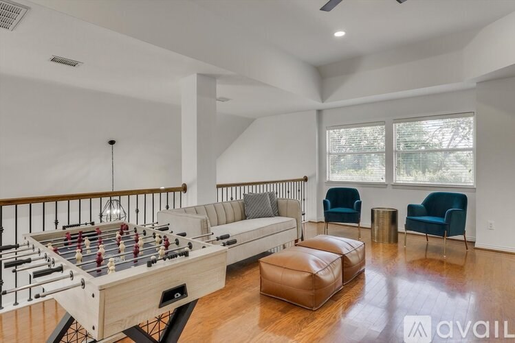 A foosball table is in the middle of a living room with a couch and chairs.