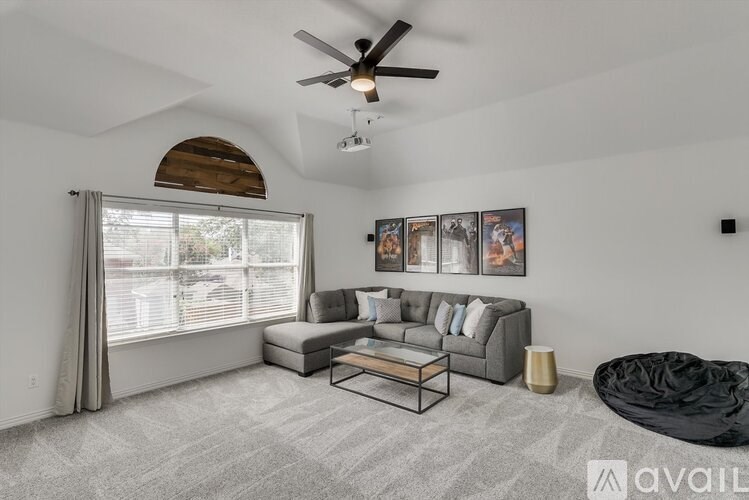 A living room with a grey sofa, a black bean bag, and a ceiling fan.