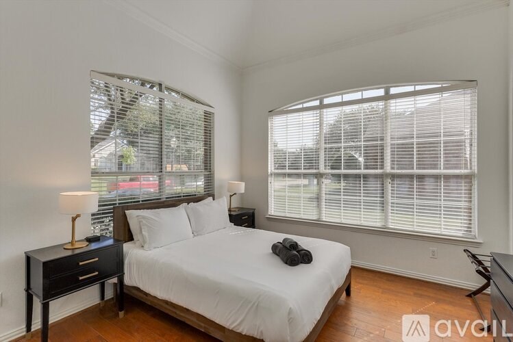 A bedroom with a bed, nightstand, and window with blinds.