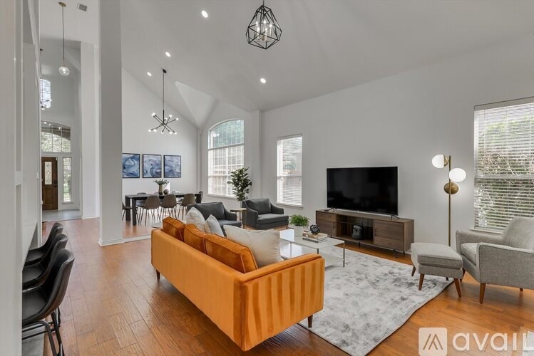 A living room with a television, couch, and chairs.