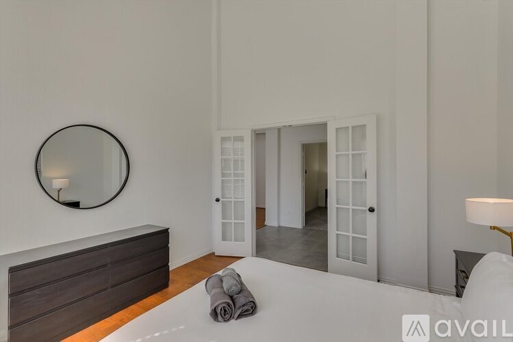 A bedroom with a round mirror on the wall and a bed with towels on it.
