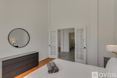 A bedroom with a round mirror on the wall and a bed with towels on it.