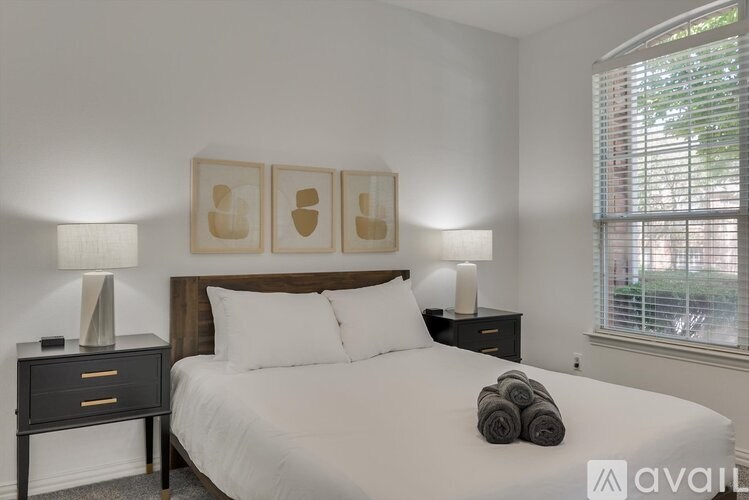 A bedroom with a large bed, two lamps, and a window with blinds.