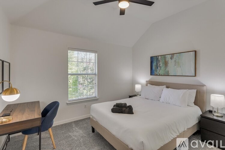 A bedroom with a bed, chair, and painting on the wall.