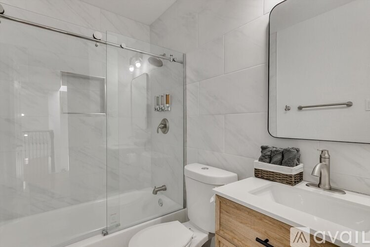 A modern bathroom with a walk-in shower, toilet, and sink.