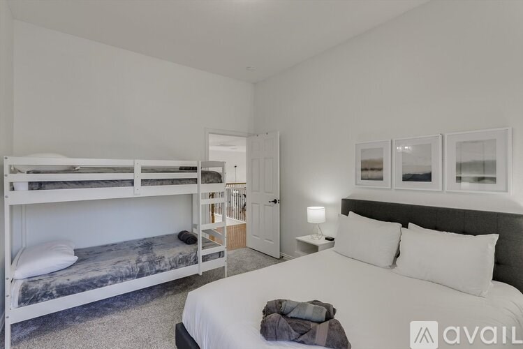 A bedroom with a white bed and a bunk bed with a grey blanket.