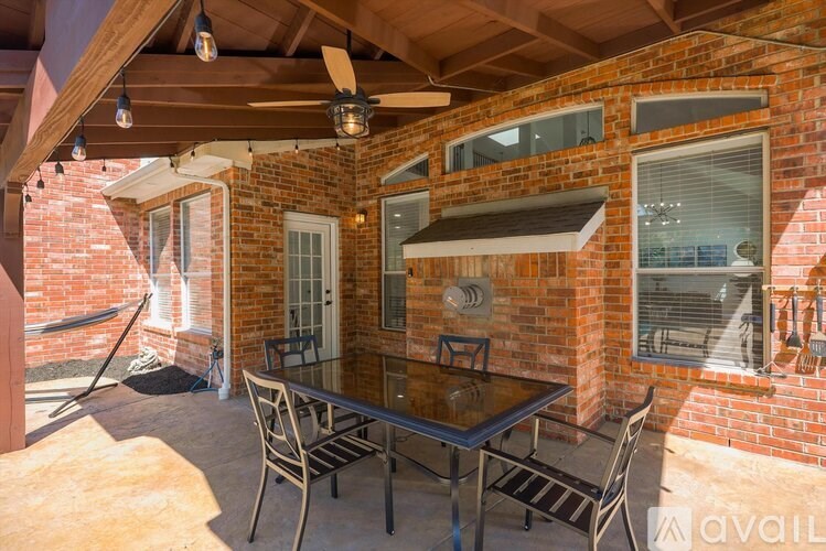 A patio with a table and chairs is covered by a roof.