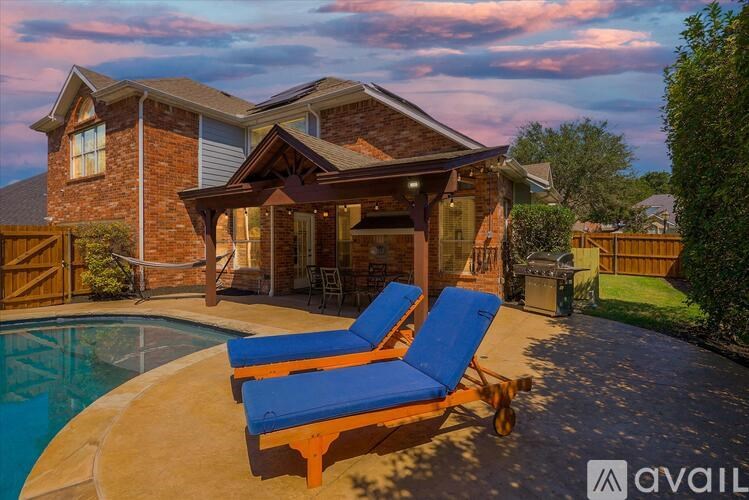 A house with a pool and two lounge chairs.