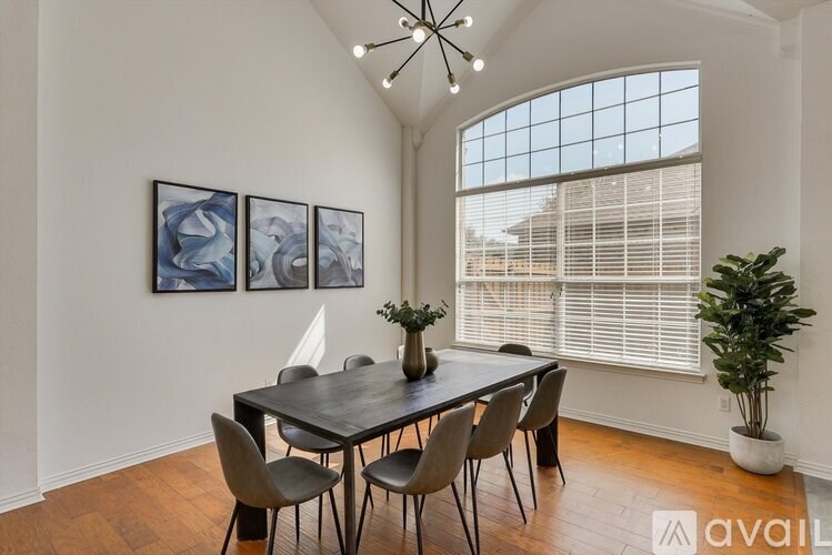 A dining room with a table set for four and a chandelier.