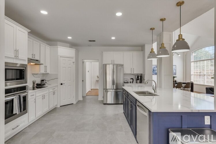 A modern kitchen with white cabinets and a blue island.