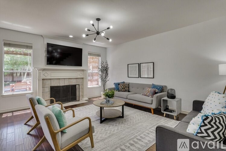 A living room with a fireplace and a television mounted above it.