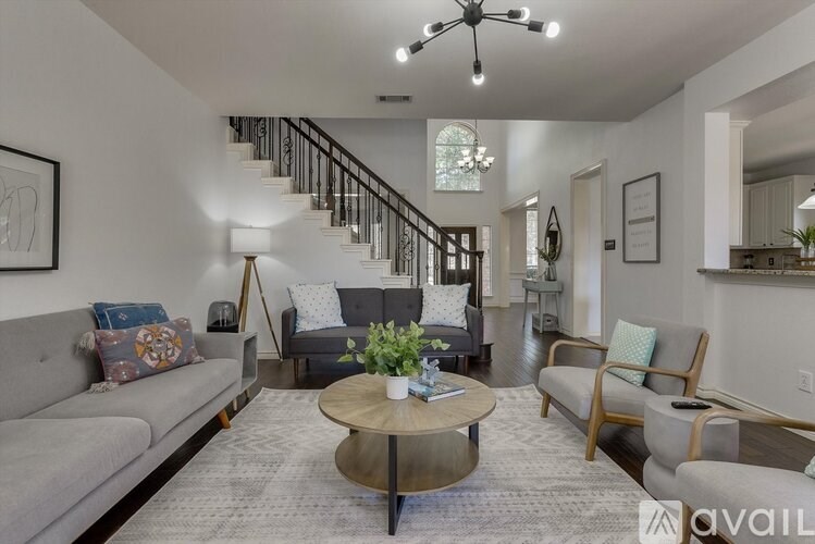A living room with a grey couch, a coffee table, and a staircase.